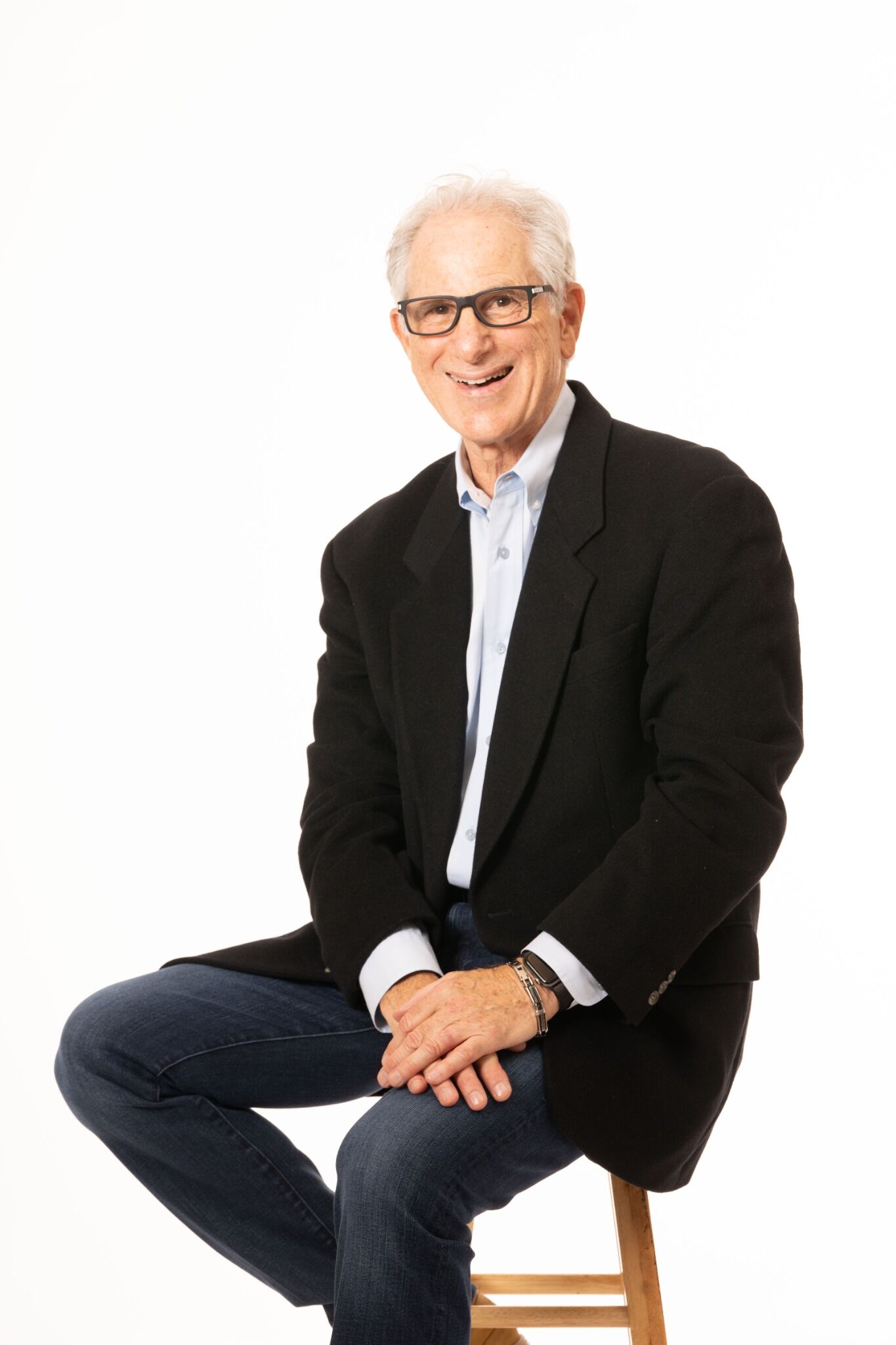 DW Starr smiling in a sport coat, seated on a stool